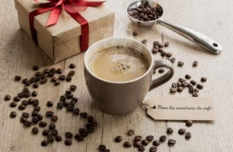 Composition flat lay de cadeaux café avec tasse fumante, grains de café, accessoires barista et paquet cadeau sur table en bois
